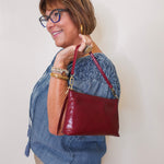 Woman holding a red handbag against a plain background
