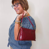 Woman holding a red handbag against a plain background