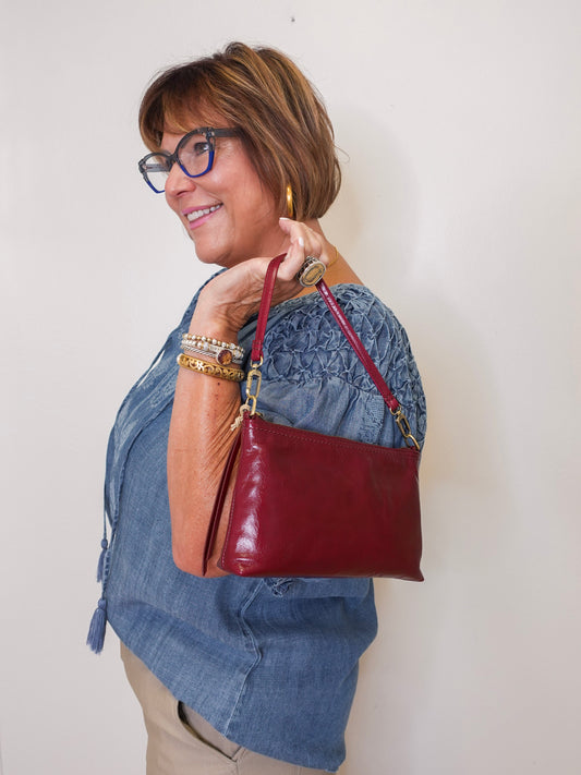 Woman holding a red handbag against a plain background
