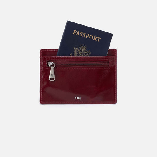 Maroon wallet with a passport inside on a light gray background