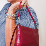 Person holding a red handbag with a neutral background