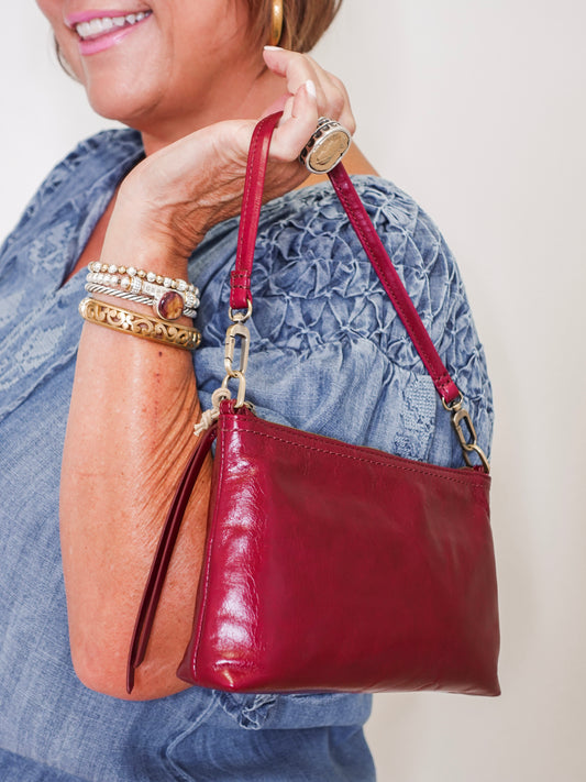Person holding a red handbag with a neutral background