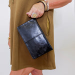 Person holding a black clutch with a plain background