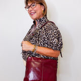 Woman wearing a leopard print top and red leather skirt against a white background
