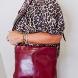 Person wearing a leopard print jacket and holding a red leather bag indoors.