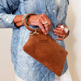 Person holding a brown handbag wearing a blue denim jacket.
