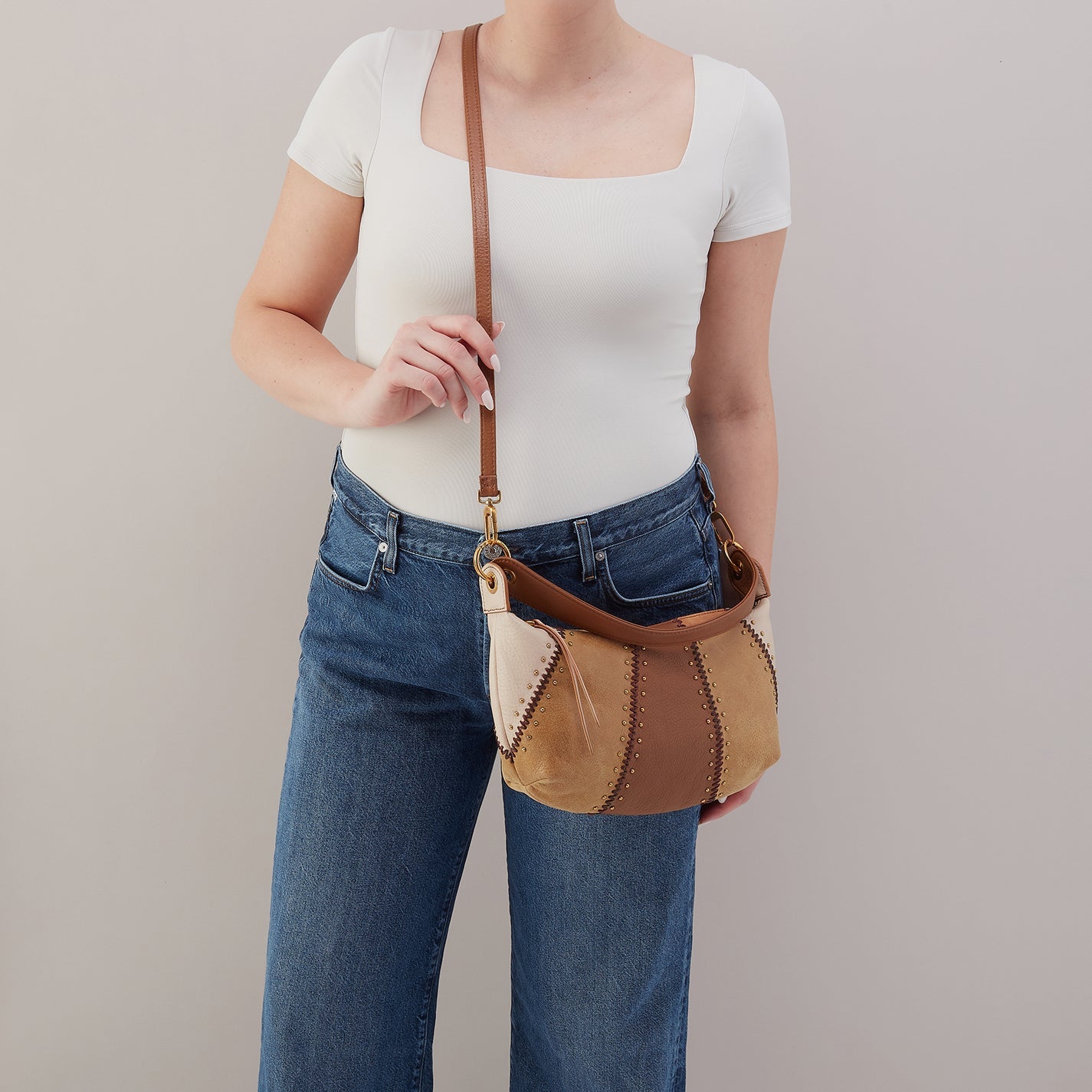 Person holding a brown leather handbag against a plain background