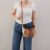 Person holding a brown leather handbag against a plain background
