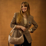 Woman holding a beige handbag against an orange background