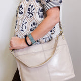 woman wearing the hobo pier aniline gloss shoulder bag against a white background.