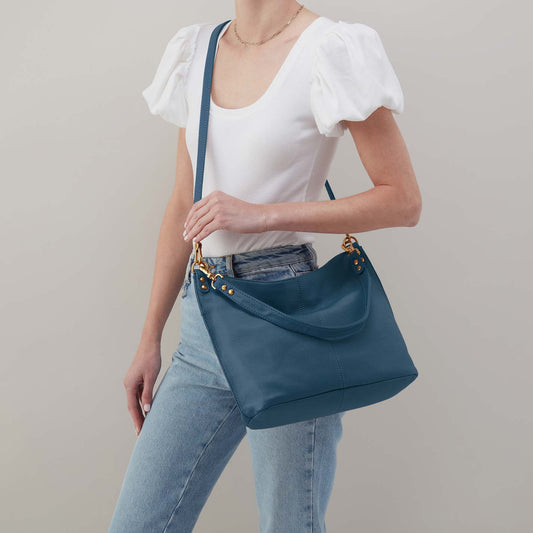 Person holding a blue handbag against a plain background