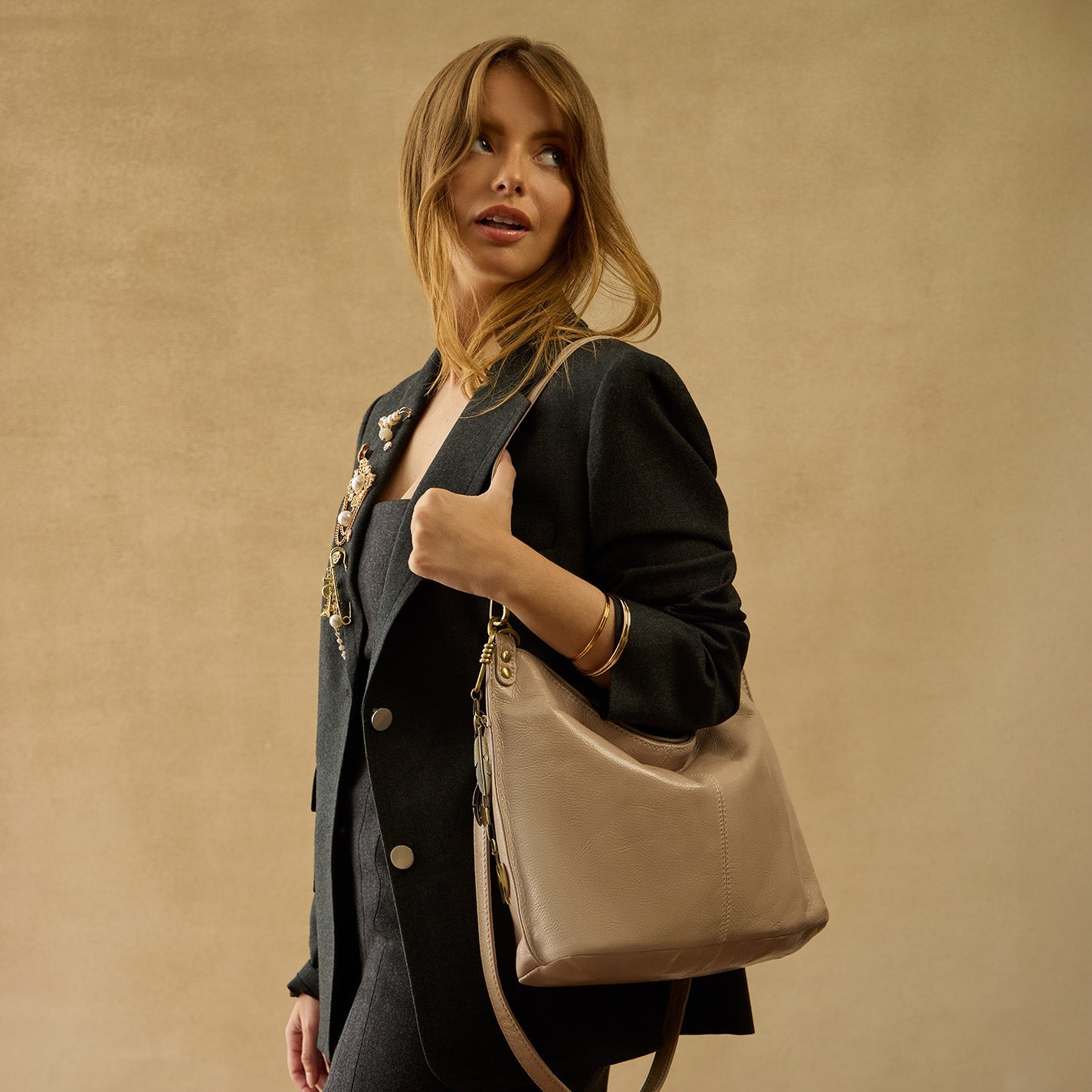 Woman holding a beige handbag against a beige background