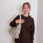 woman wearing the hobo bag render shoulder bag against a white wall.