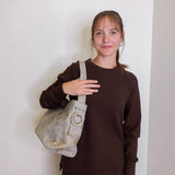 woman wearing the hobo bag render shoulder bag against a white wall.