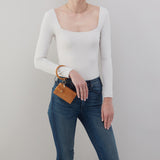Person wearing a white long-sleeve top and blue jeans, holding a brown leather wallet.