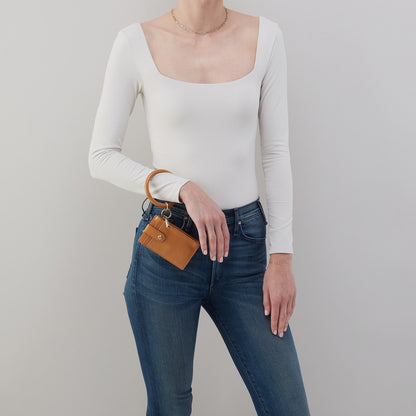 Person wearing a white long-sleeve top and blue jeans, holding a brown leather wallet.
