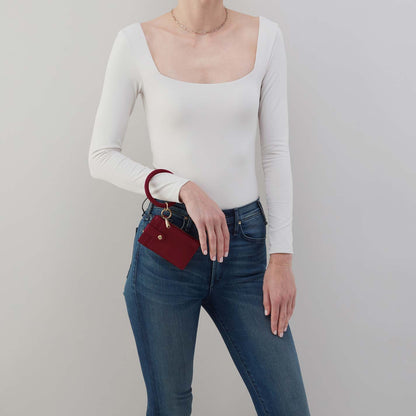Person wearing a white long-sleeve top and blue jeans, holding a red wallet.