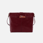 Maroon leather handbag with a brown pocket on a light gray background