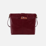 Maroon leather handbag with a brown pocket on a light gray background