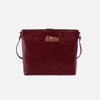 Maroon leather handbag with a brown pocket on a light gray background