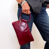 Person holding a maroon handbag against a plain background