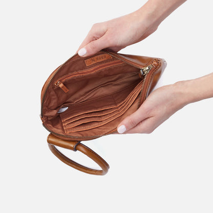 Brown leather clutch held by a hand on a light gray background