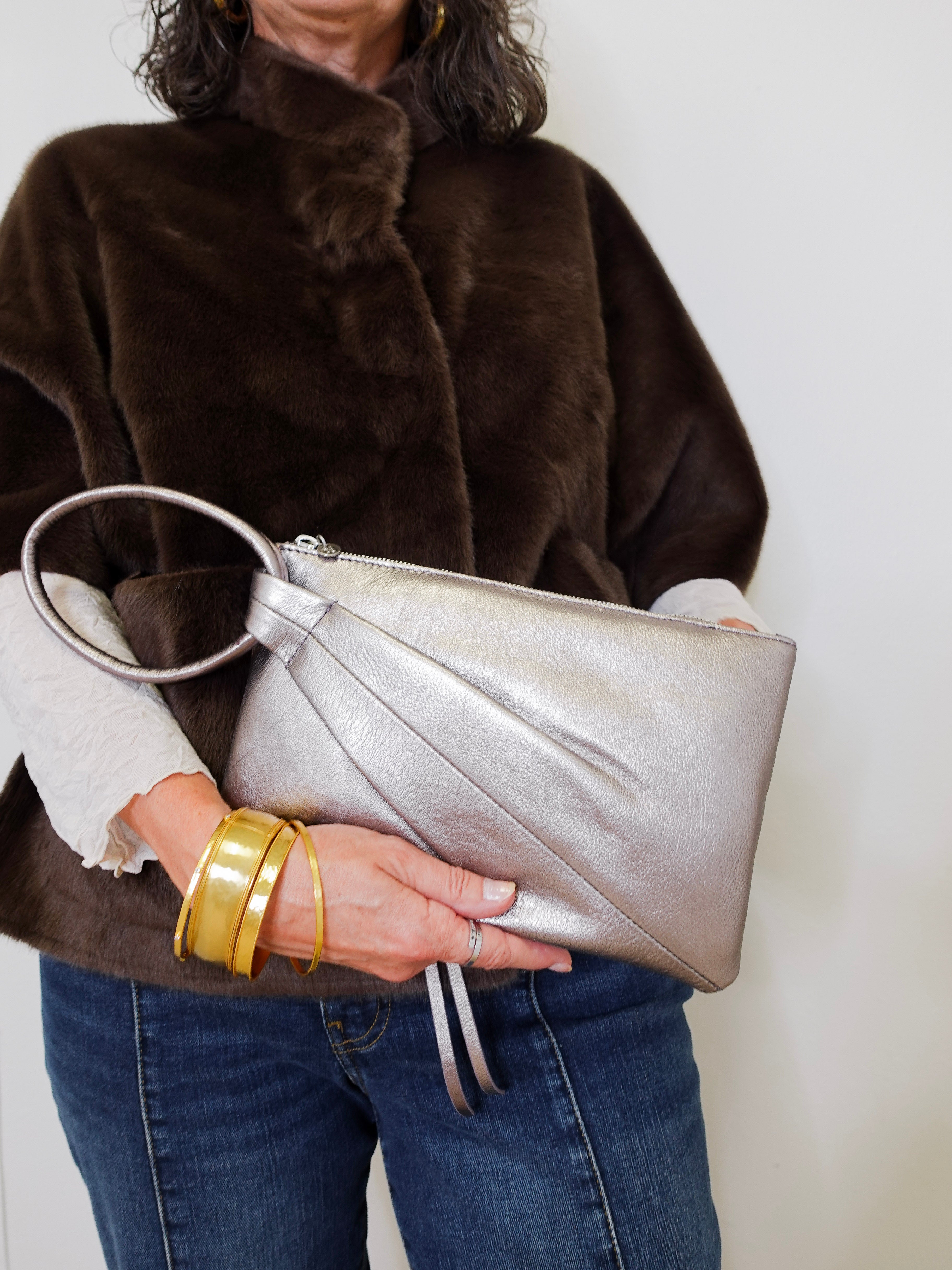 Person holding a silver clutch with a plain background
