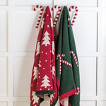 Two Christmas-themed towels hanging on a rack against a white tiled wall.