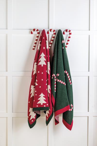Two Christmas-themed towels hanging on a rack against a white tiled wall.