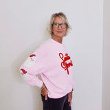 Person wearing a pink sweatshirt with red text and graphics against a white background