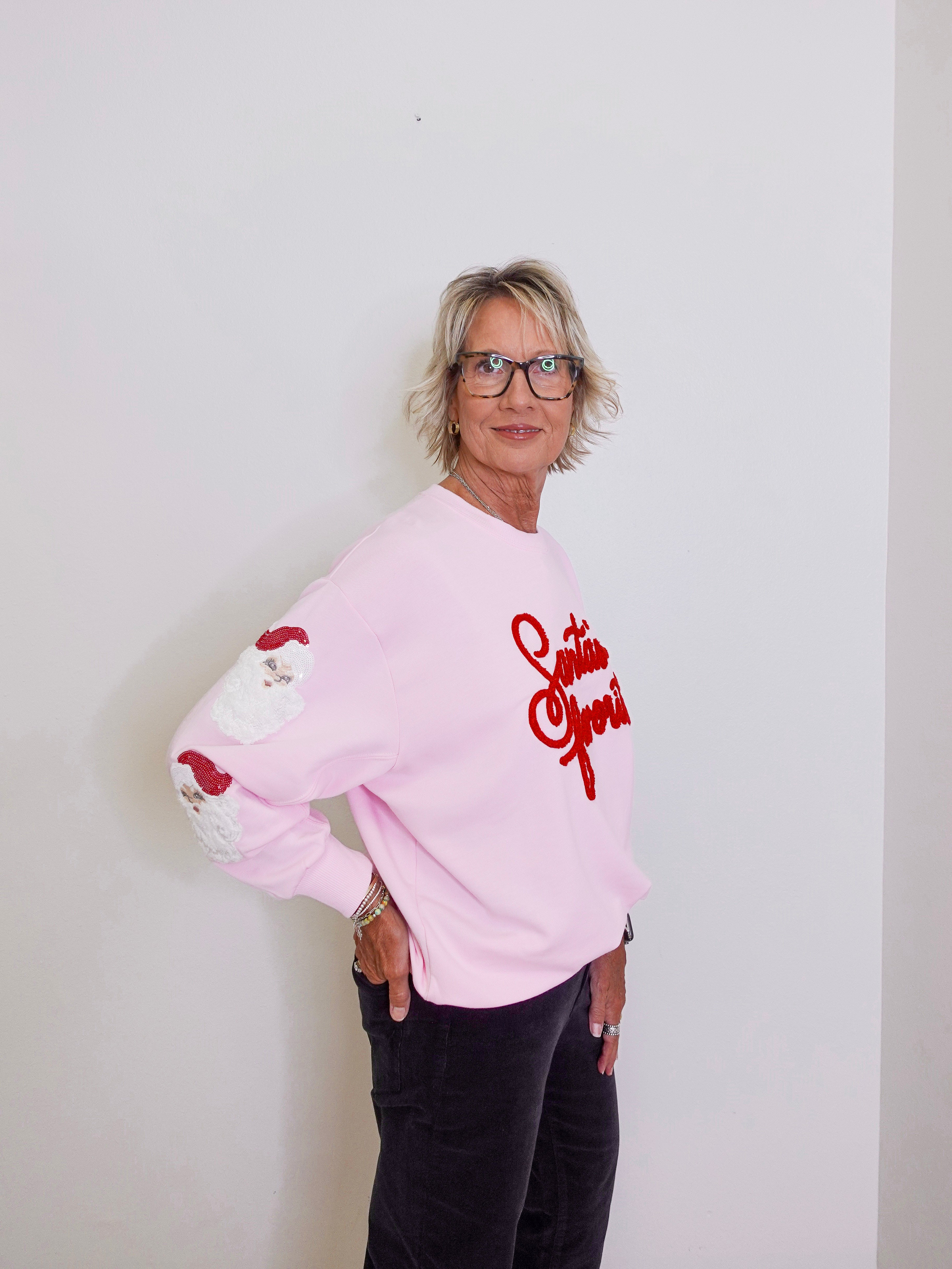 Person wearing a pink sweatshirt with red text and graphics against a white background