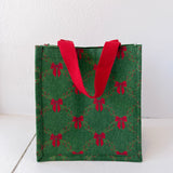 Green gift bag with red bow pattern and red handles on a white background