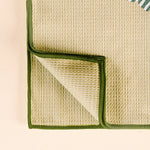 Close-up of a textured green and beige fabric with a folded corner on a light background
