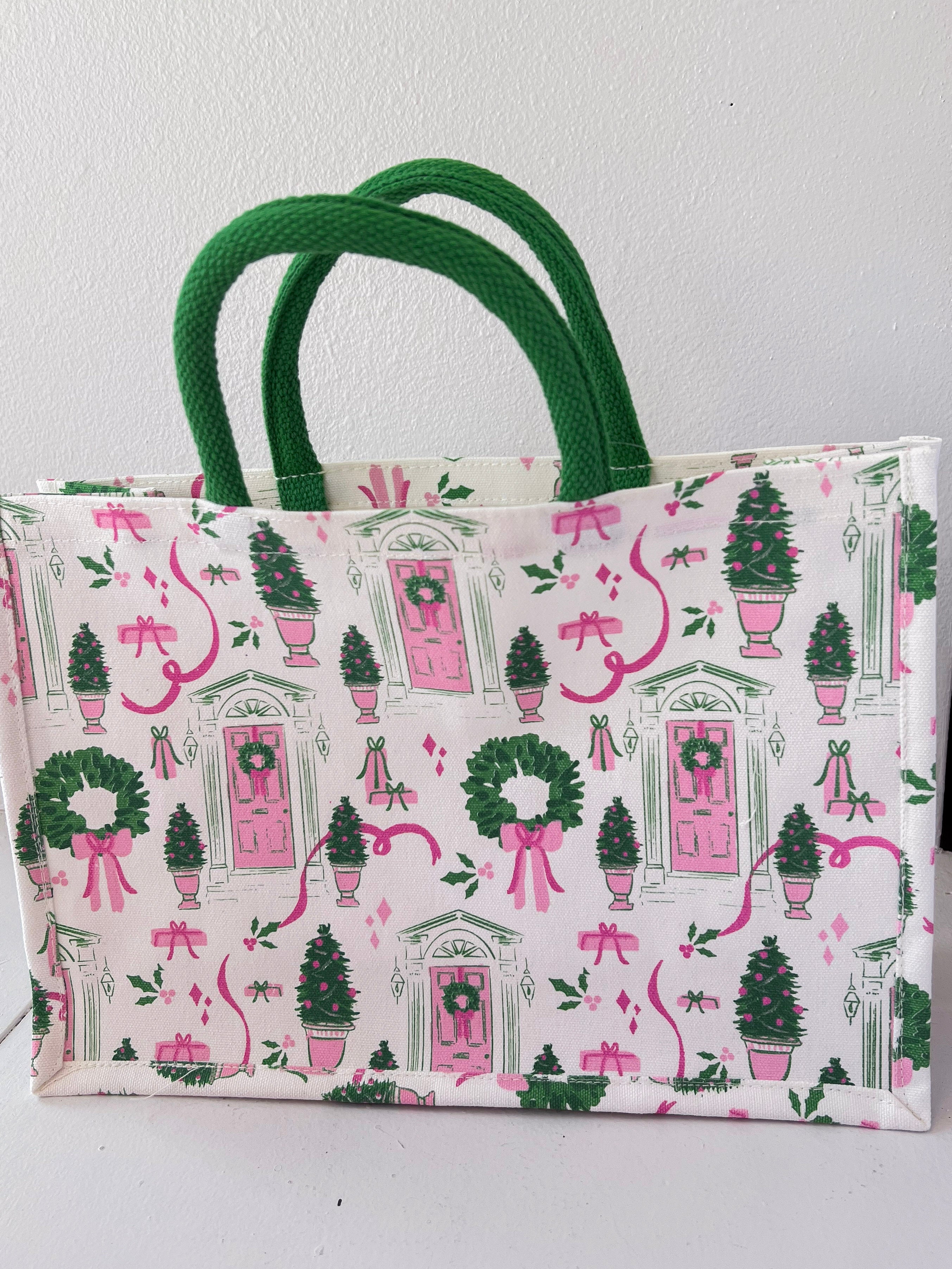 Tote bag with festive design featuring trees, wreaths, and pink bows on a white background