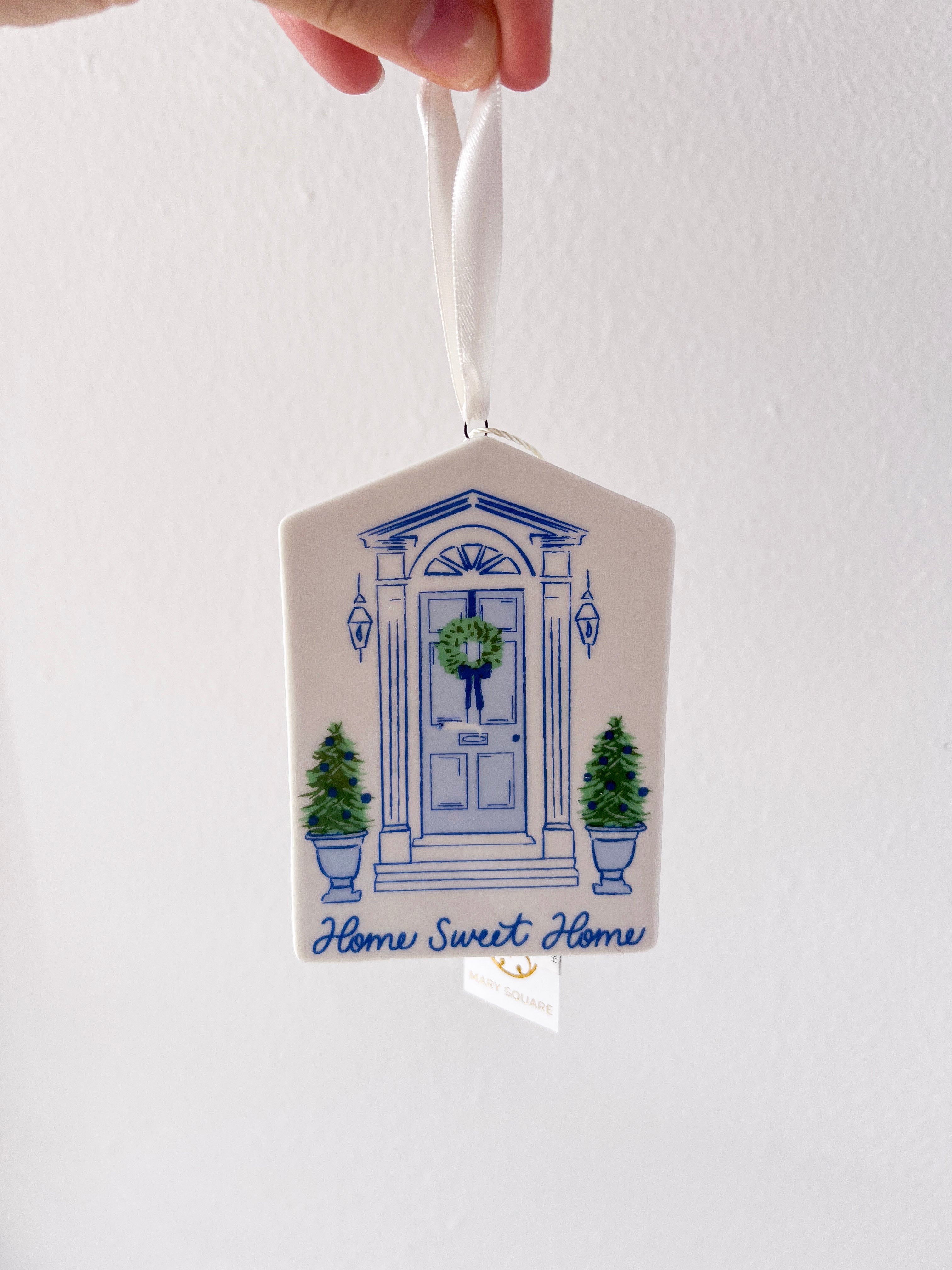 Decorative hanging ornament with blue door and wreath design on a white background