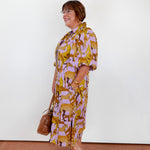 Woman wearing a patterned dress with a white wall background