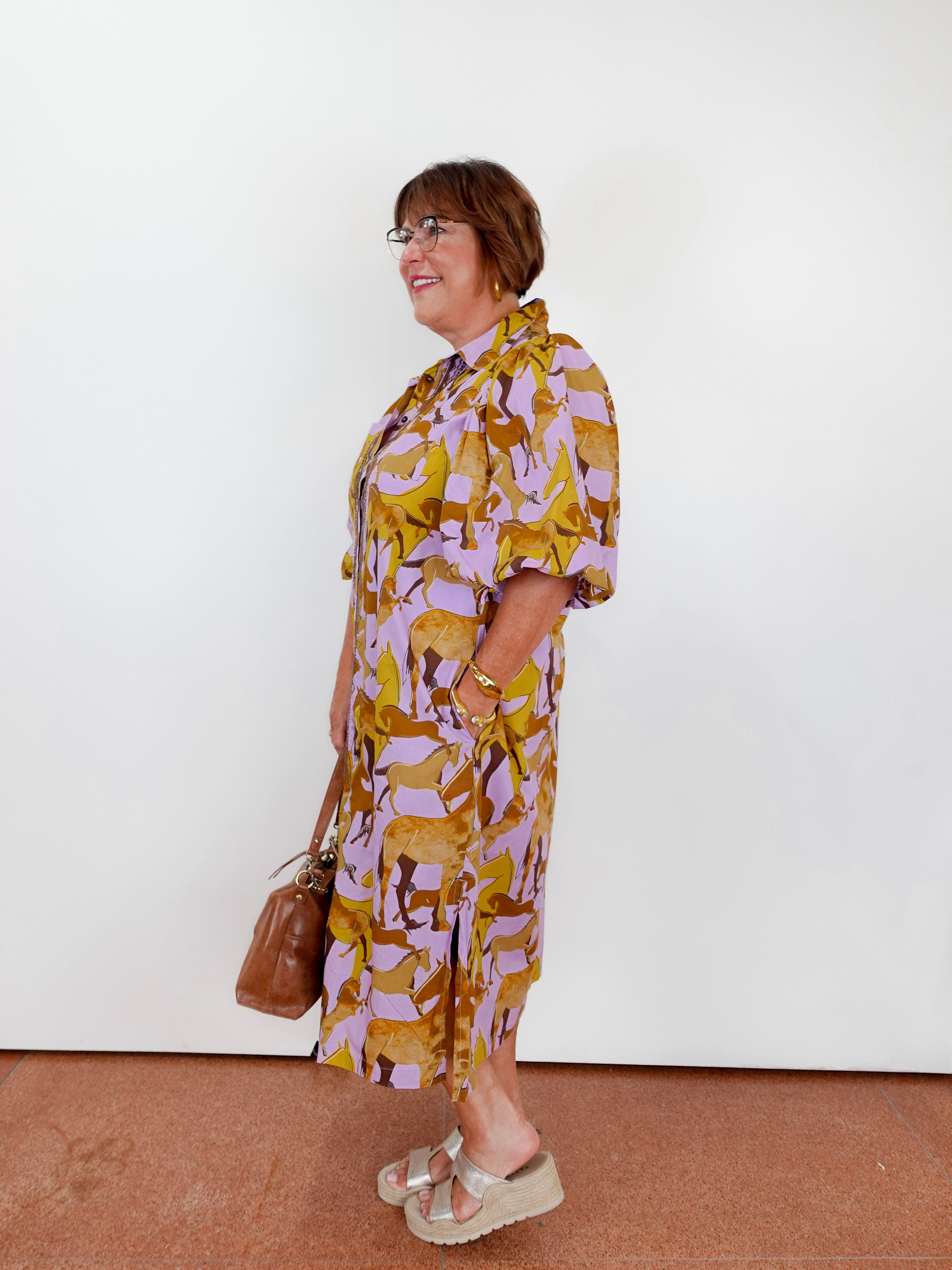 Woman wearing a patterned dress with a white wall background
