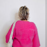 Person wearing a bright pink fuzzy sweater against a white background