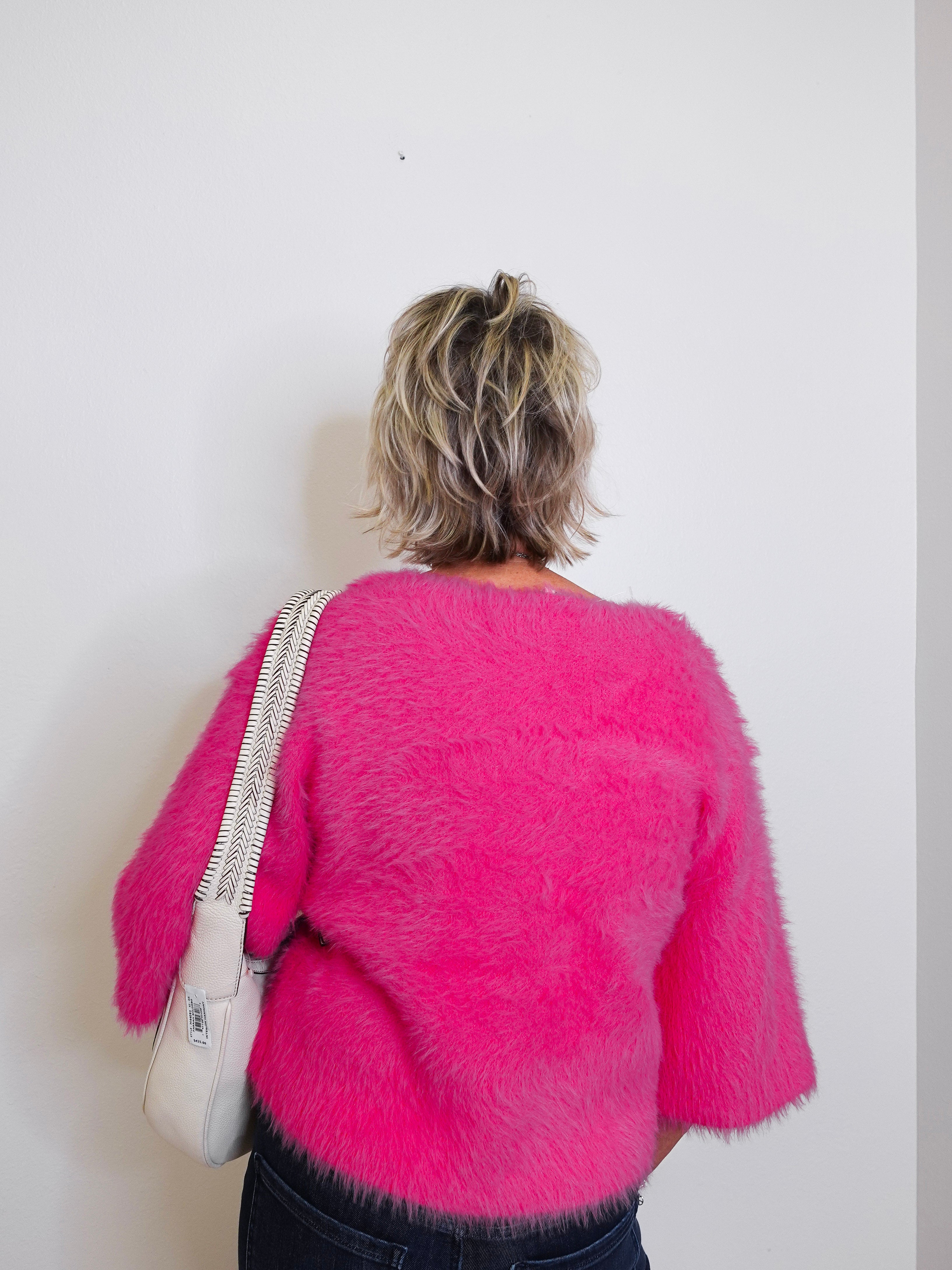 Person wearing a bright pink fuzzy sweater against a white background