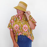 Person wearing a patterned top and hat against a white background