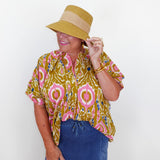 Person wearing a patterned top and hat against a white background