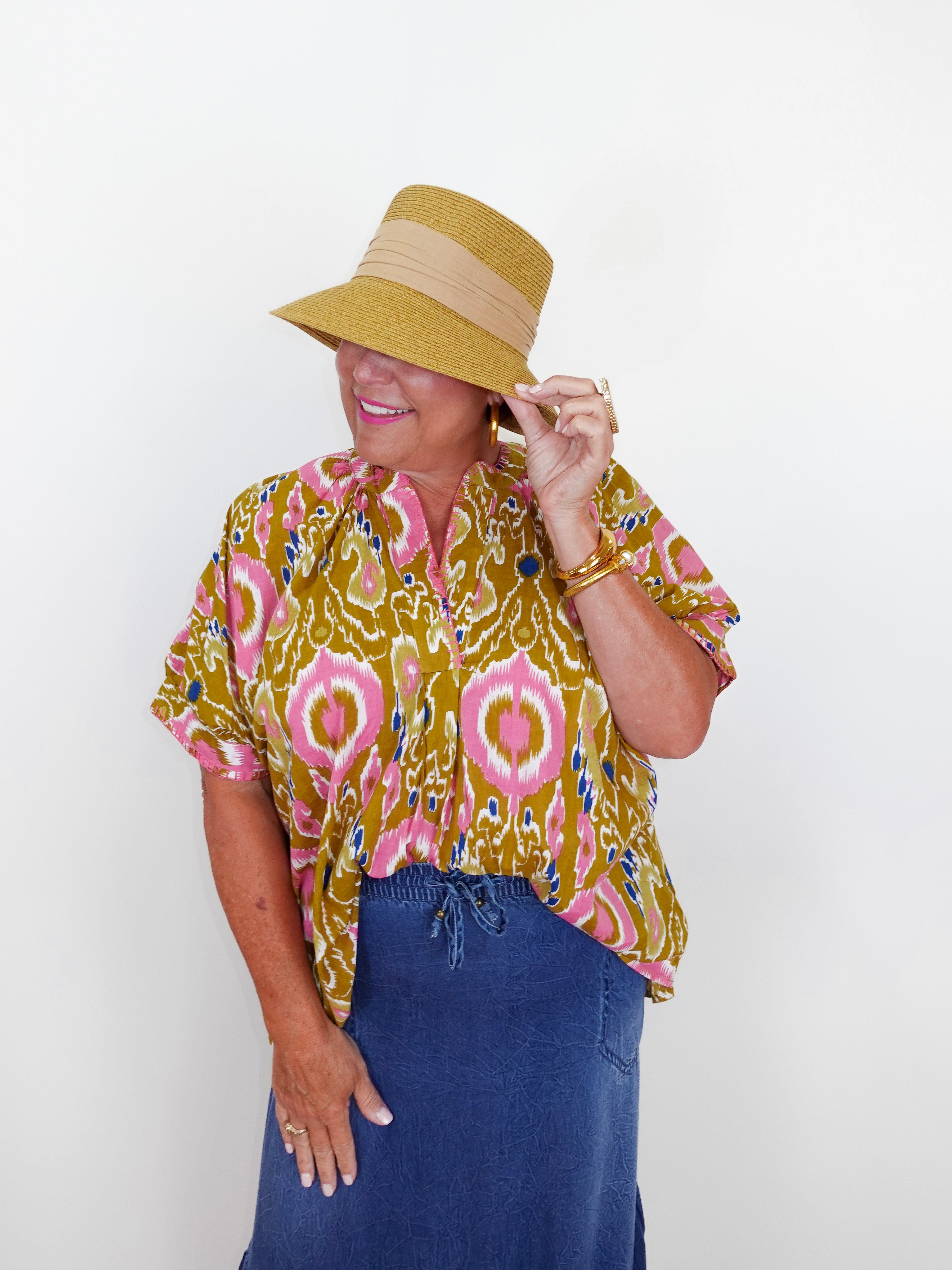 Person wearing a patterned top and hat against a white background
