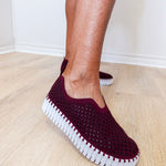 A woman wearing a maroon ilse Jacobsen flat against a white background. 