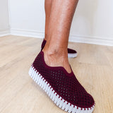 A woman wearing a maroon ilse Jacobsen flat against a white background. 