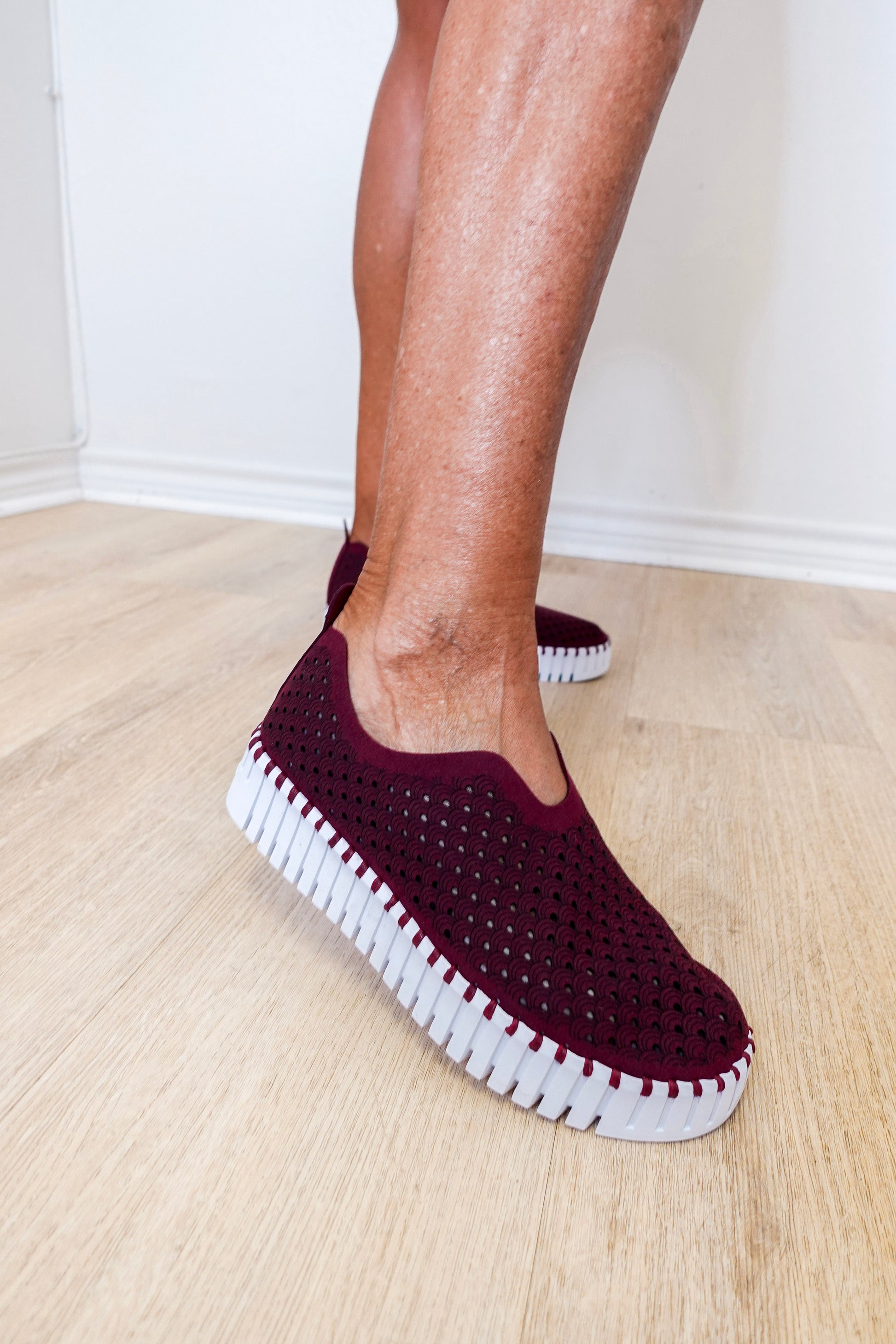 A woman wearing a maroon ilse Jacobsen flat against a white background. 