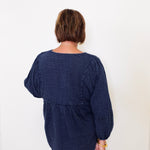 Person wearing a navy blue textured dress against a white background