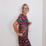Woman wearing a floral dress against a plain white wall