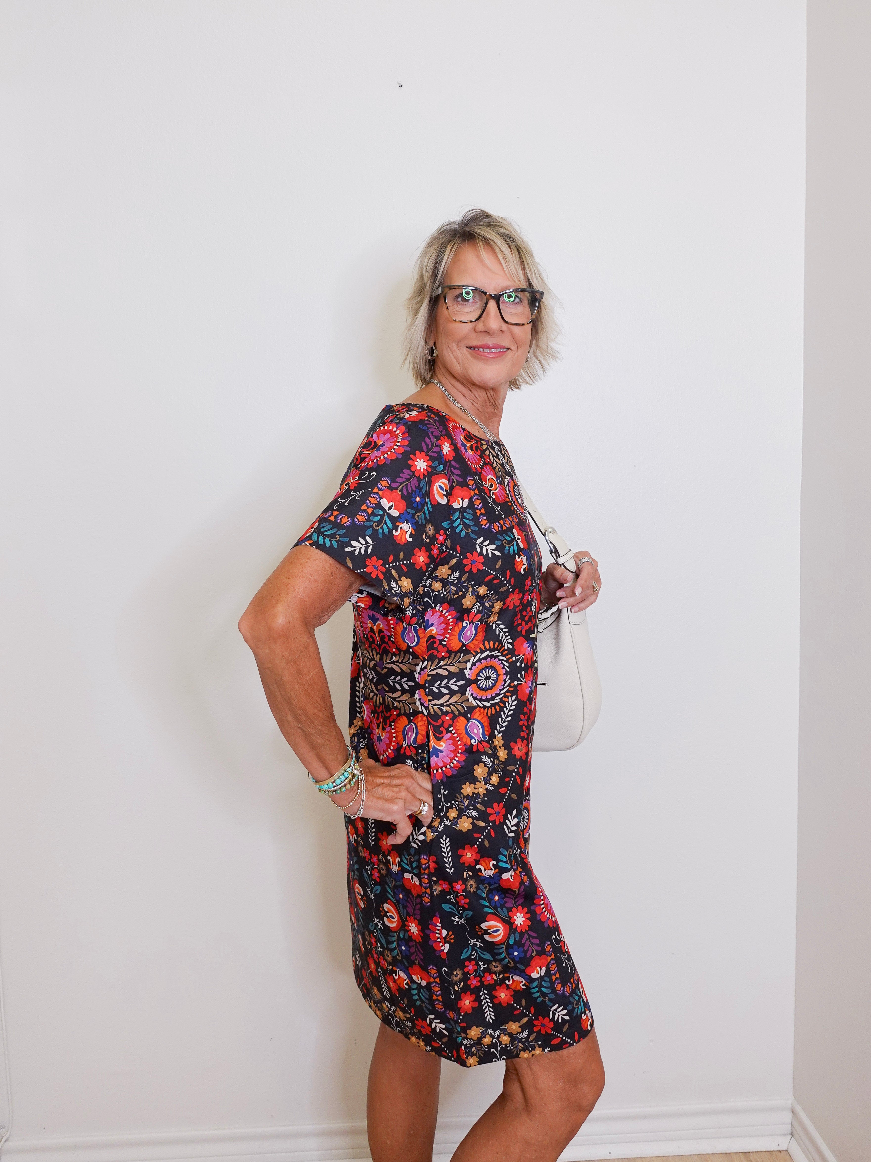 Woman wearing a floral dress against a plain white wall