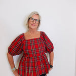 woman wearing a plaid blouse against a white background. 
