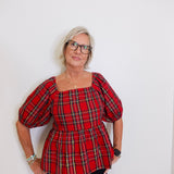 woman wearing a plaid blouse against a white background. 